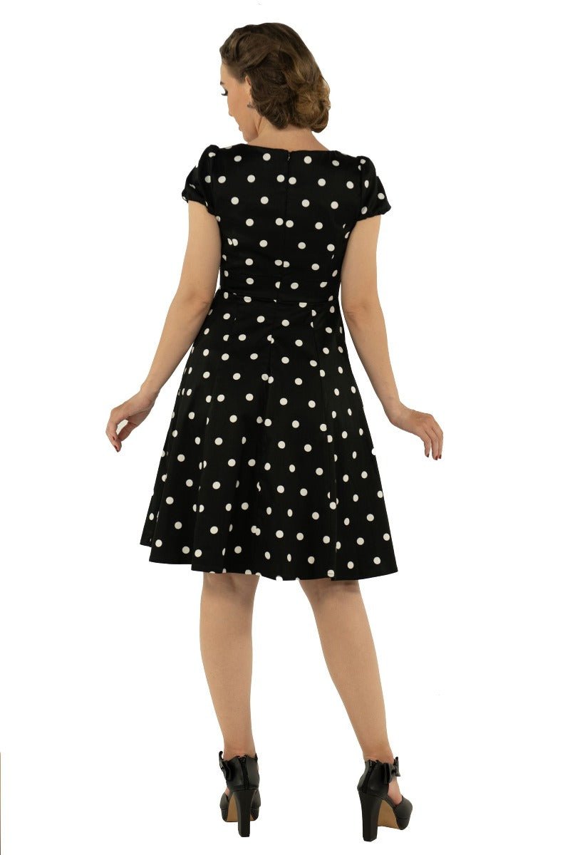Model wears the Claudia short sleeve dress, in black, with white polka dots, back view
