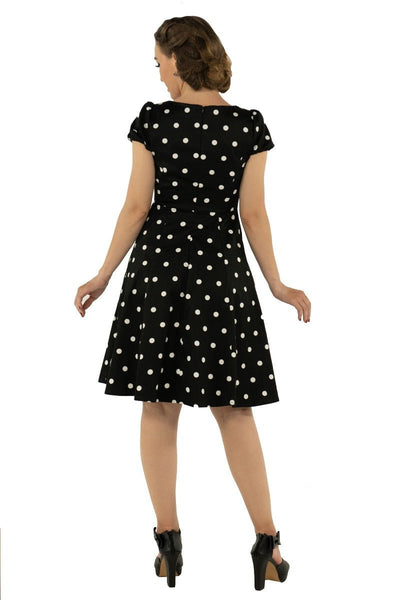 Model wears the Claudia short sleeve dress, in black, with white polka dots, back view