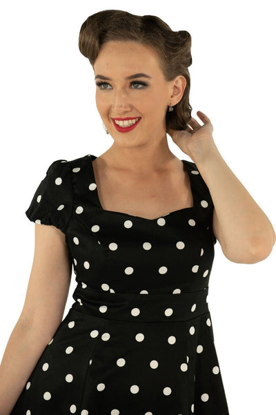 Model wears the Claudia short sleeve dress, in black, with white polka dots, close up view