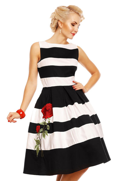 Model wears the black and white striped Annie swing dress, with embroidered red rose on the skirt, front view