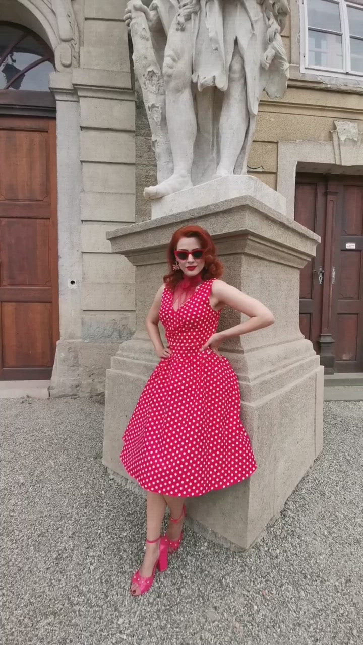 Video of model wearing our May crossover bust dress, in red/white polka dot print, in front of a statue