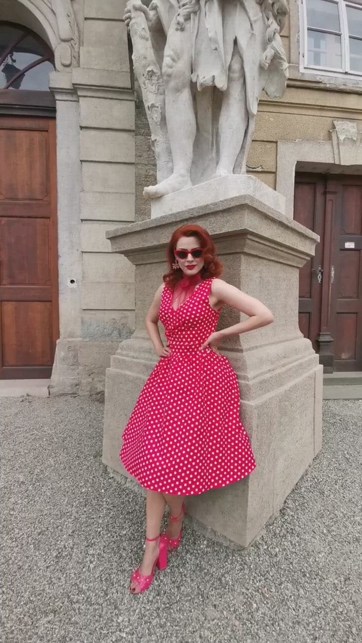 Video of model wearing our May crossover bust dress, in red/white polka dot print, in front of a statue
