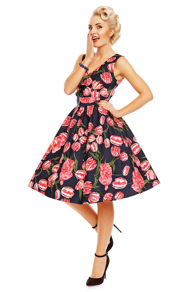 Model wearing May V neck floral dress, in navy blue, with pink tulips, side view