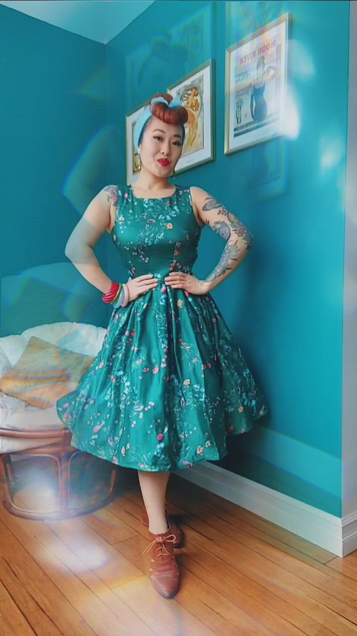 Video of a model playfully showing a green sleeveless with bird print dress.