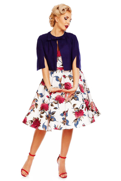 Model wearing Grace pleated bust dress, in white, with red roses, front view, with blue cape