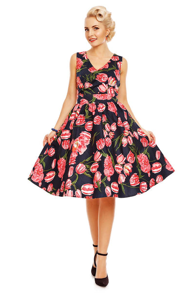 Model wearing May V neck floral dress, in navy blue, with pink tulips, front view
