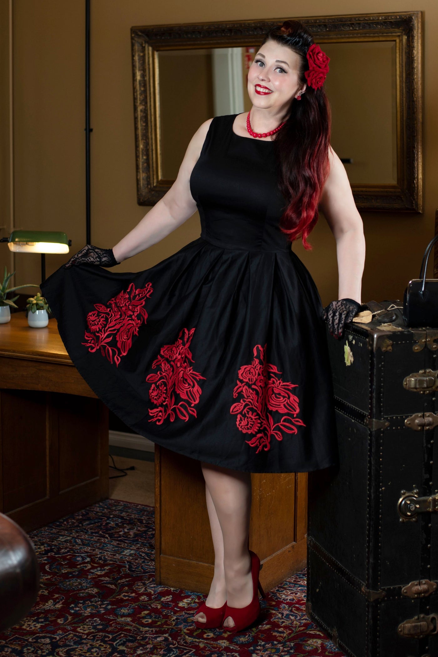 Woman wearing Annie Embroidered Roses Swing Dress in Black/Red, in front of a mirror