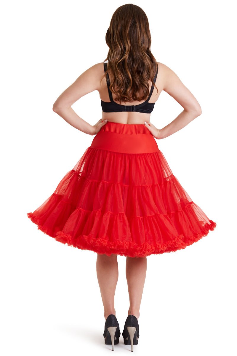 Woman wears a red knee length petticoat, with black accessories, back view