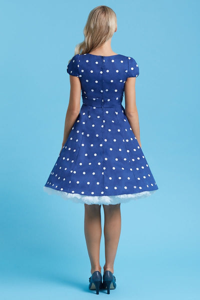 Model wears the dark blue Claudia dress, with white polka dots, with a petticoat, back view