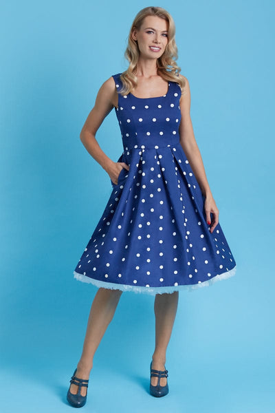 Model wears the Amanda fit and flare dress in dark blue, with white polka dots, front view, hand in pocket