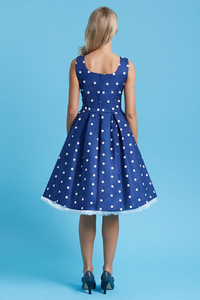 Model wears the Amanda fit and flare dress in dark blue, with white polka dots, back view