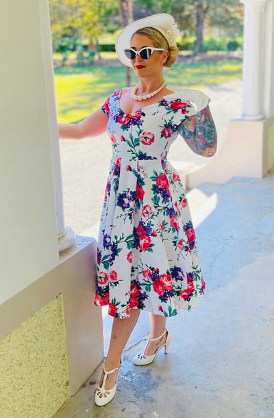 woman wearing our Lily, off-shoulder 50's Evening Dress in White, with pink and purple flowers
