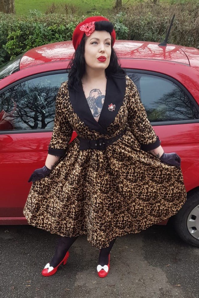 Woman wearing our tiffany lapel coat dress, in brown leopard print, win front of a red car