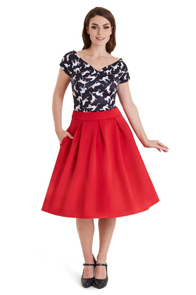 Model wears our V neck, short sleeved, off shoulder top, in black, with white cats print, with a red skirt, front view