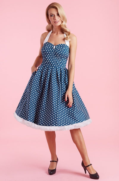 Model wears our halterneck Sophia dress, in blue, with white polka dots, front view