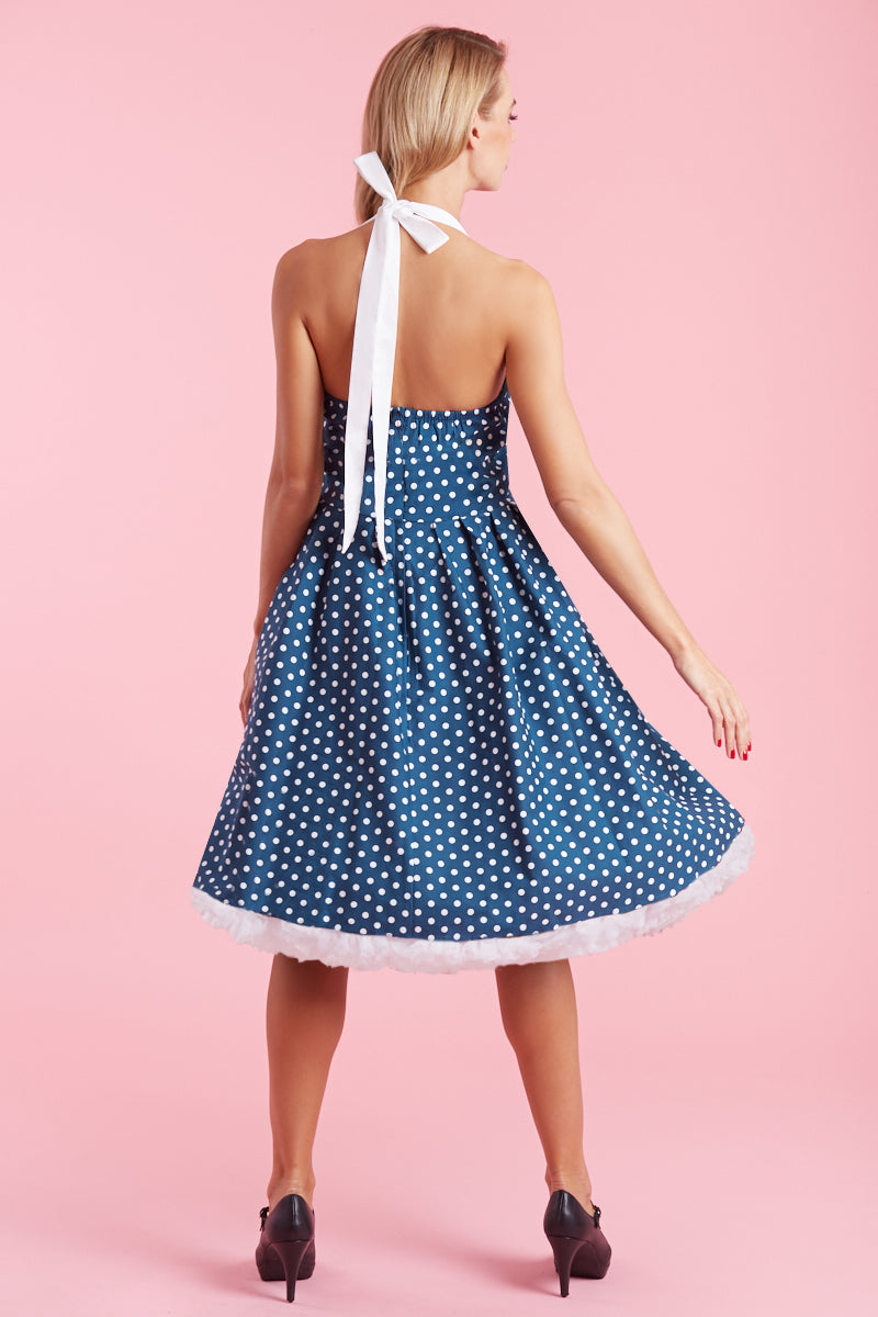 Model wears our halterneck Sophia dress, in blue, with white polka dots, back view