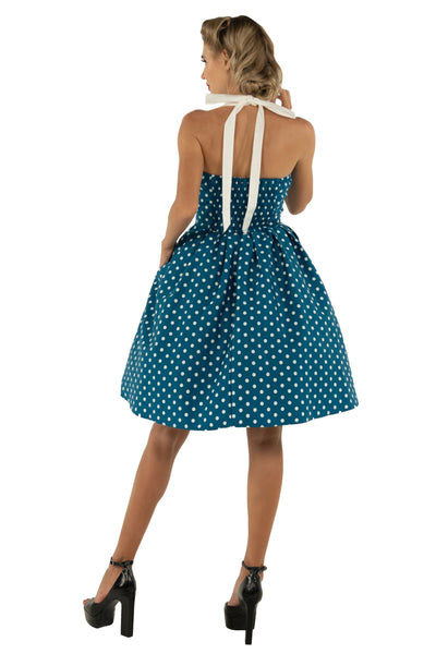 Model wears our halterneck Sophia dress, in blue, with white polka dots, backview