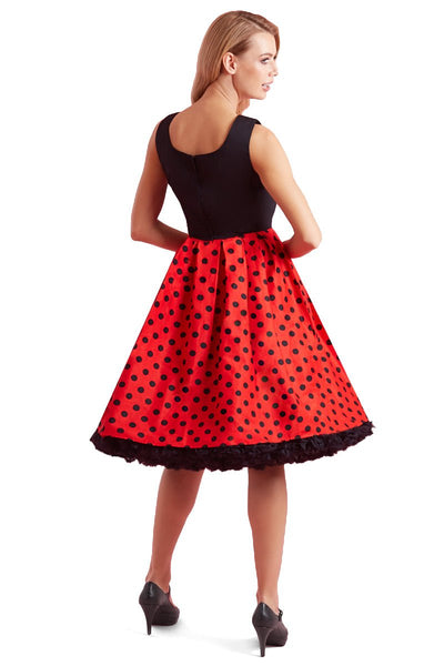 Model wears our sleeveless Amanda dress, with black top and red skirt, with black polka dot spots, back view