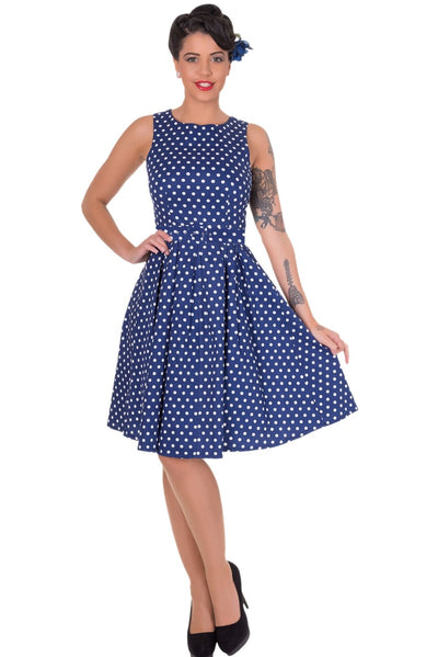 Model wears our sleeveless Lola dress, in dark blue, with white polka dots, front view