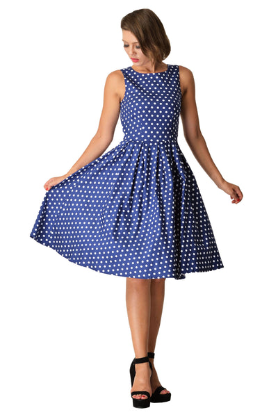 Model wears our sleeveless Lola dress, in dark blue, with white polka dots, front view