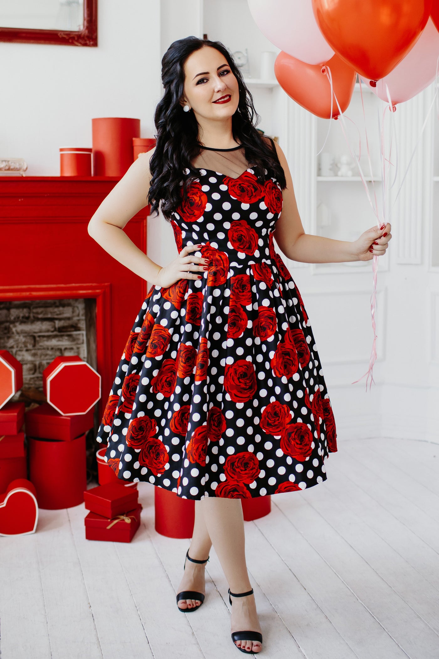 Woman wearing Vintage Style Polka Roses Party Dress in Black/Red, holding red and pink balloons