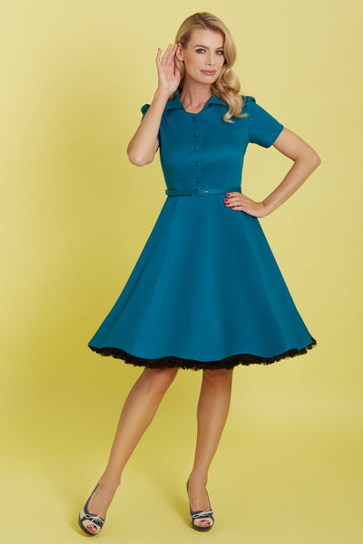 Model wearing our short sleeved Penelope button top dress in teal blue, with petticoat, front view