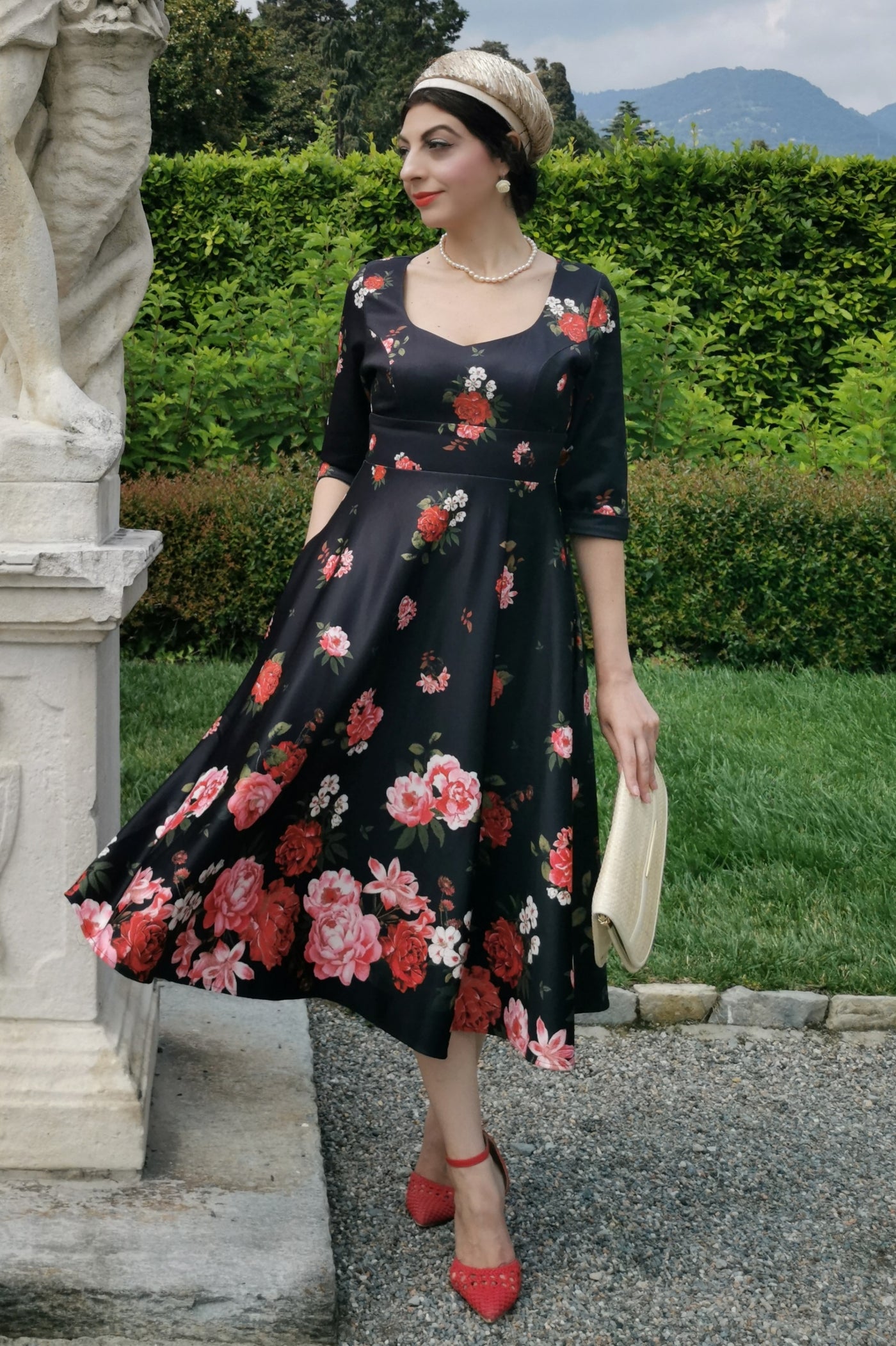 Woman wears our long sleeved, midi dress in black/pink floral print, in a public space