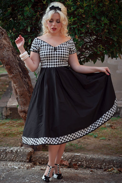 Woman wears our short sleeved Lily dress, in black and white check gingham print on top, in front of a tree