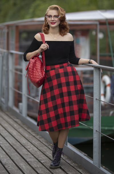 Woman wearing black top, red tartan skirt and doc martens