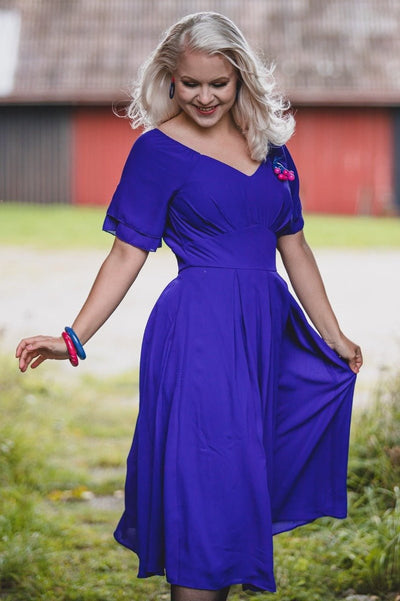 Woman wears Meredith floaty casual dress, with short sleeves, in dark blue, with accessories