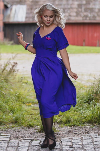Woman wears our Meredith floaty casual dress, with short sleeves, in dark blue, with accessories