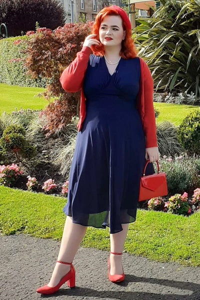 Woman wearing our Elise 40's casual day dress, in dark blue, with red accessories