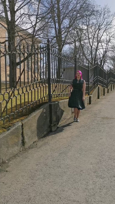 Video of a model twirling and hopping wearing a green tartan dress