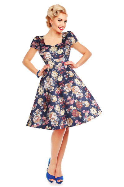 Model wearing our cap sleeve Claudia dress, in navy blue, with beige flowers, front view