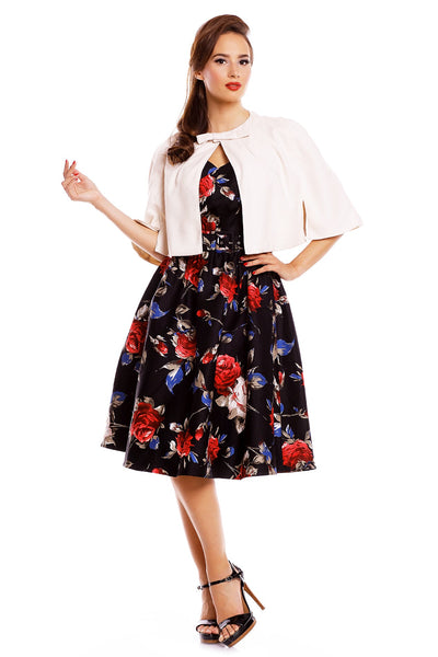 Model wearing our Sabrina cape in beige, with a floral dress underneath, front view