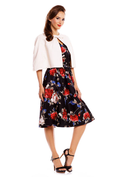 Model wearing our Sabrina cape in beige, with a floral dress underneath, side view