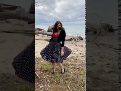 Woman wearing our Grace sleeveless dress, in black, with white polka dots, front view