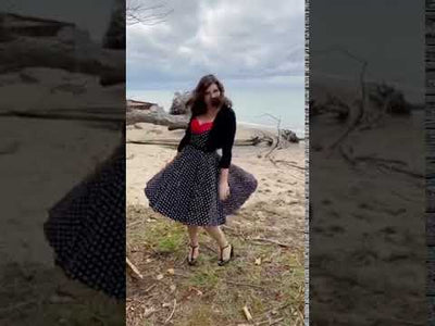 Woman wearing our Grace sleeveless dress, in black, with white polka dots, front view