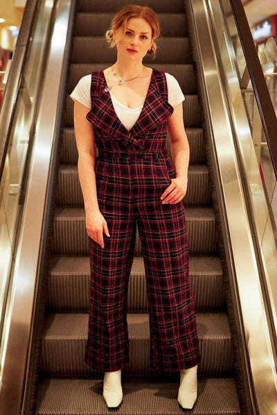 Influencer wearing blue red tartan jumpsuit on an escalator