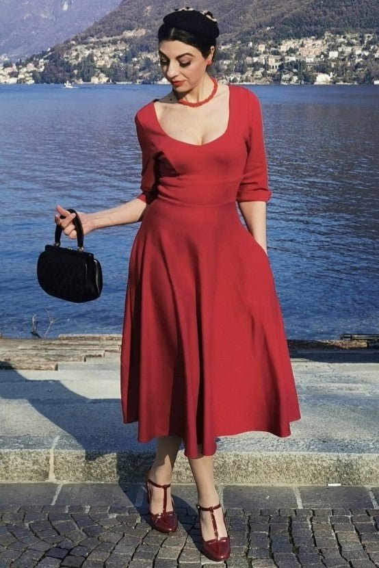 Blogger wears our long sleeved midi dress, in burgundy red, in front of the sea and an island