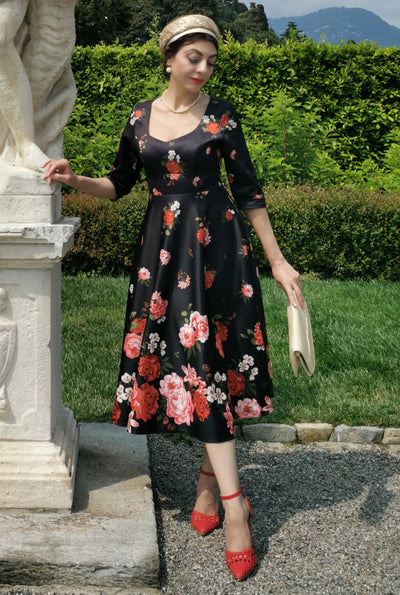 Woman wears our long sleeved, midi dress in black/pink floral print, in a public space
