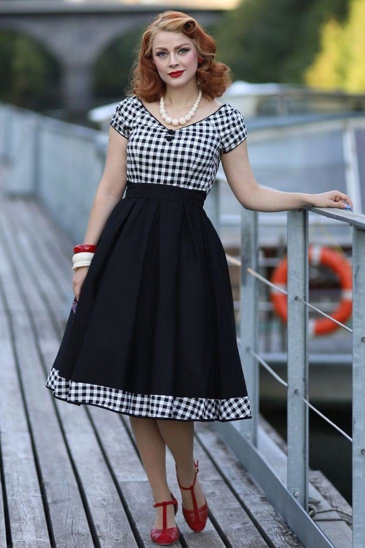 Woman wears our Off Shoulder Black/White Gingham Swing Dress, on a bridge