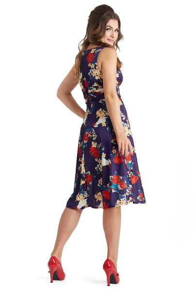 Model wears our Bernice sleeveless swing dress in navy blue, with red and white flowers and parrots, back view