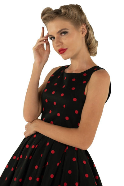 Model wears our Annie swing dress, in black, with red polka dots, close up view