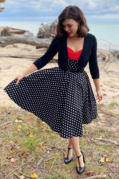 Woman wearing our Grace sleeveless dress, in black, with white polka dots, front view
