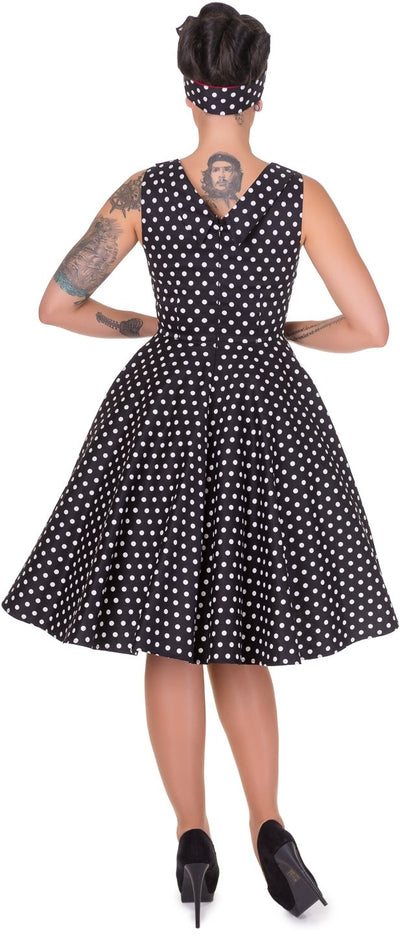 Model wearing our Grace sleeveless dress, in black, with white polka dots, back view