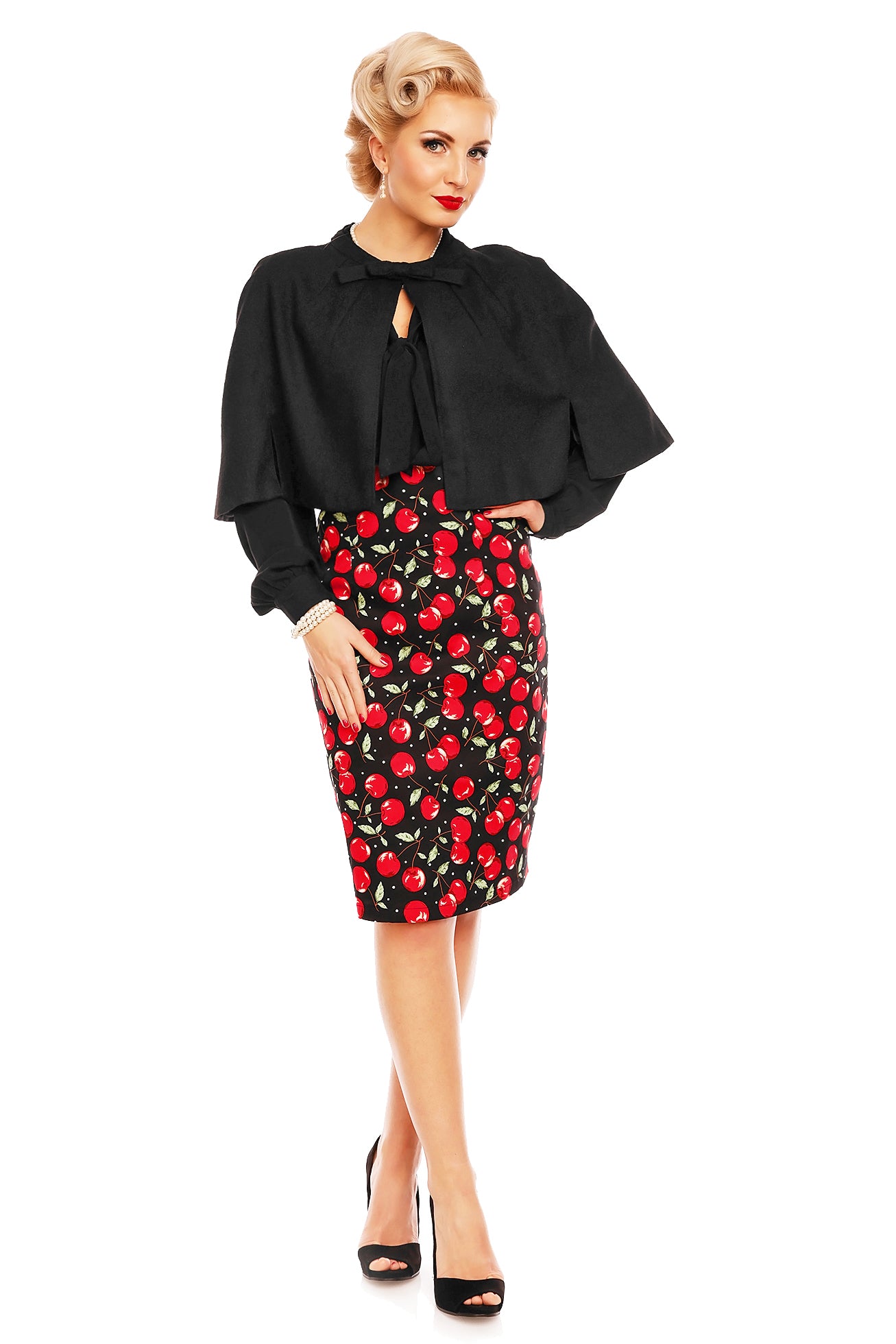 Model wears a cherry print falda pencil skirt, with cape and black top, front view