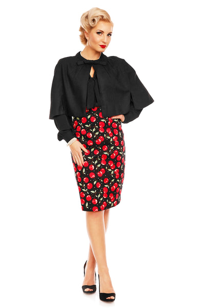 Model wears a cherry print falda pencil skirt, with cape and black top, front view