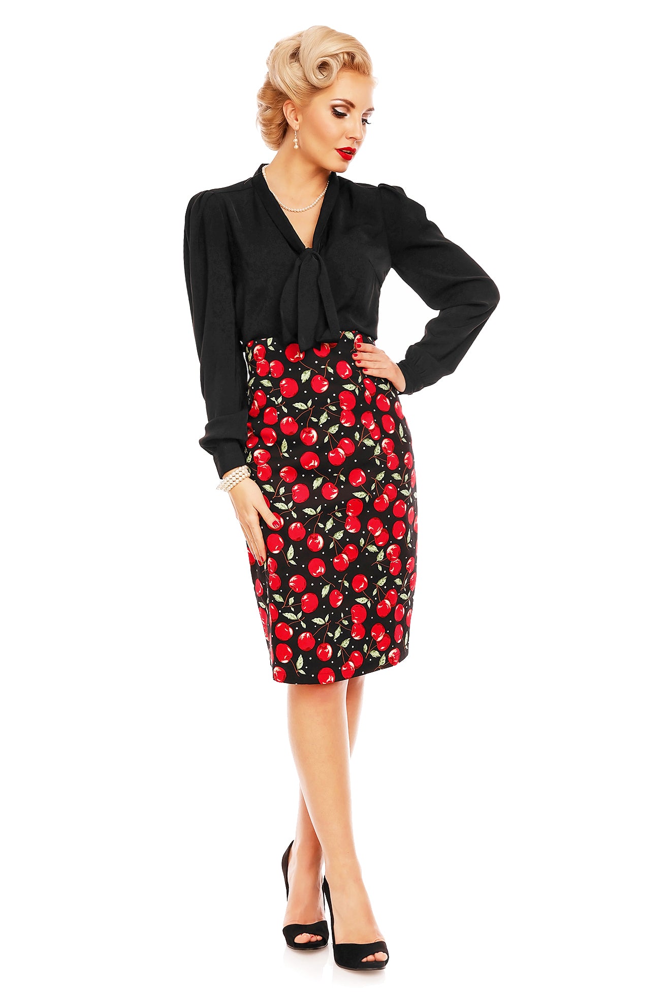 Model wears a cherry print falda pencil skirt, with cape and black top, front view