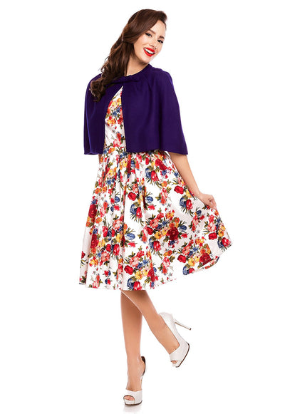 Model wearing our dark blue Sabrina cape shrug, over a white floral dress, front view